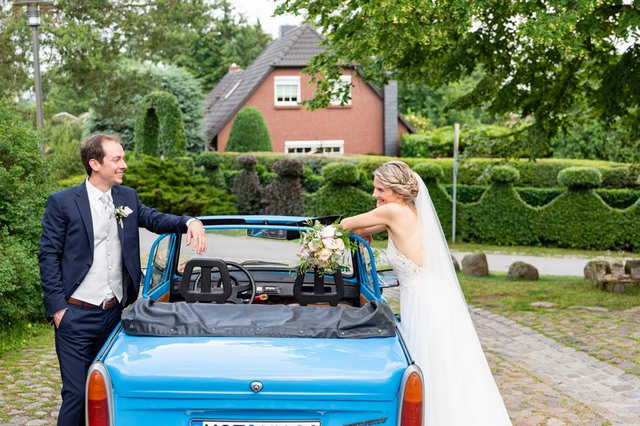 Brautpaar neben einem blauen Auto